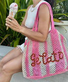 A woman holding an ice cream cone wearing a pink and white stripe tote bag that reads "gelato".