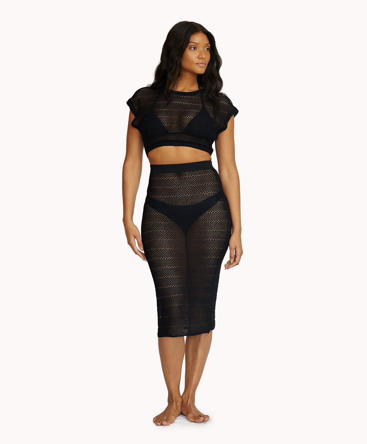 Woman wearing a matching black knit top and skirt in front of a white background.