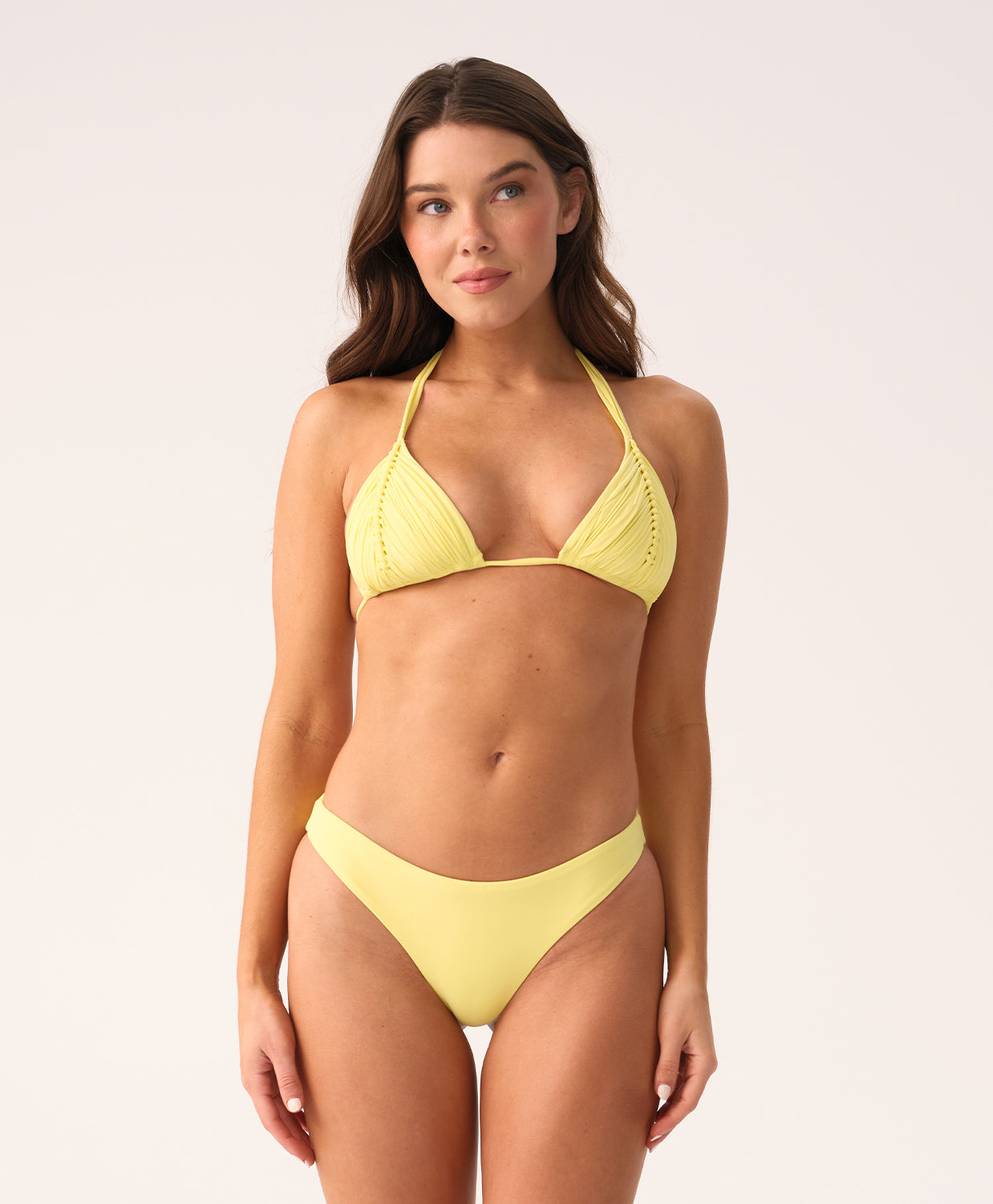 Woman wearing a yellow triangle bikini against a plain background