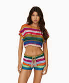 Woman wearing matching colorful, knit top and shorts in front of a white background.