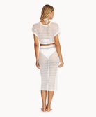 Back view of a woman wearing a matching white, knit top and skirt in front of a white background.