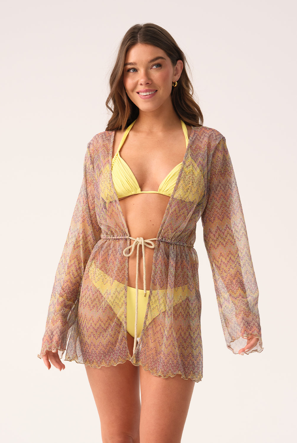 Woman wearing a yellow bikini with a matching cover-up against a white background