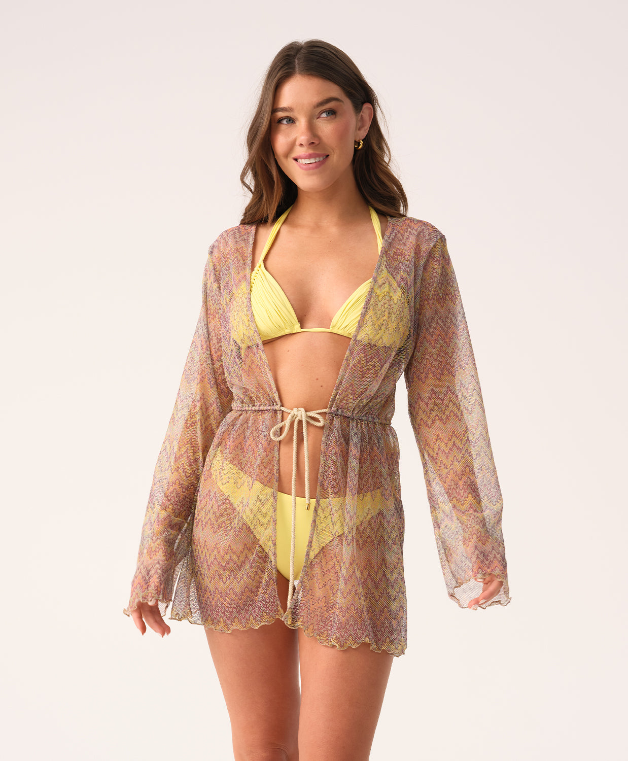 Woman wearing a yellow bikini with a matching cover-up against a white background