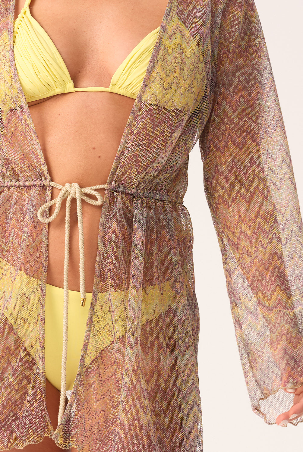 Person wearing a yellow bikini with a patterned cover-up on a white background