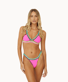Woman wearing pink crochet bikini in front of a white background.
