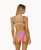 Back view of woman wearing pink crochet bikini in front of a white background.