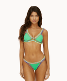 Woman wearing a green crochet bikini in front of a white background.