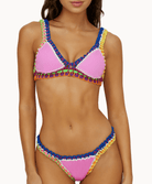 Close up of woman wearing a pink crochet bikini in front of a white background.