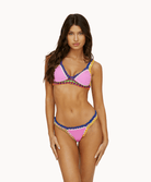 Woman wearing a pink crochet bikini in front of a white background.