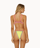Back view of woman wearing yellow crochet bikini in front of a white background.