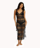 Woman wearing black lace dress in front of a white background.
