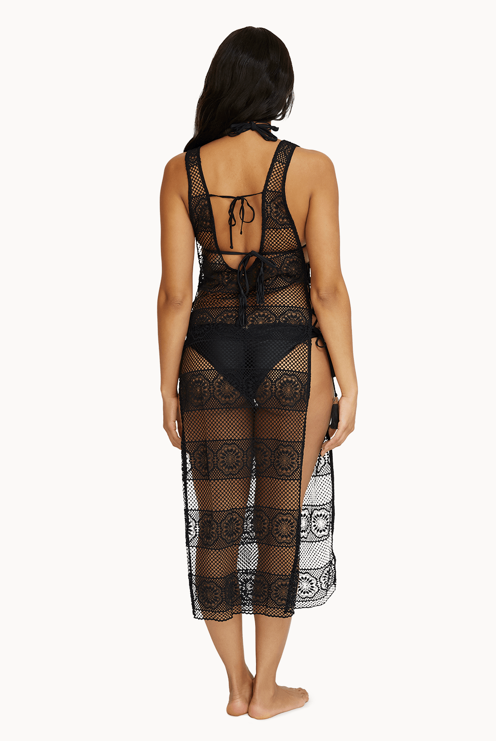 Back view of woman wearing black lace dress in front of a white background.