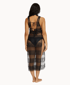 Back view of woman wearing black lace dress in front of a white background.