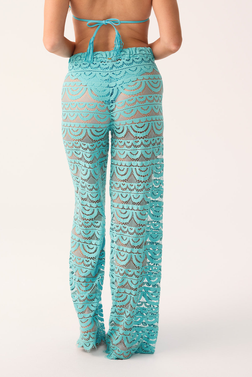 A woman's back, wearing blue high waisted pants and a bikini top on a white background