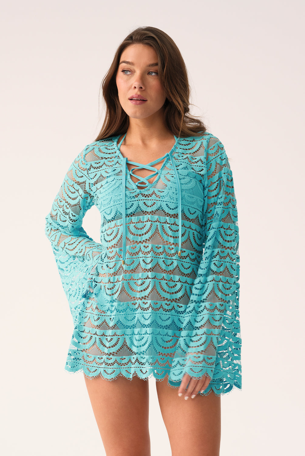 Front view of a woman modeling a light blue lace tunic with long bell sleeves and a lace-up neckline.