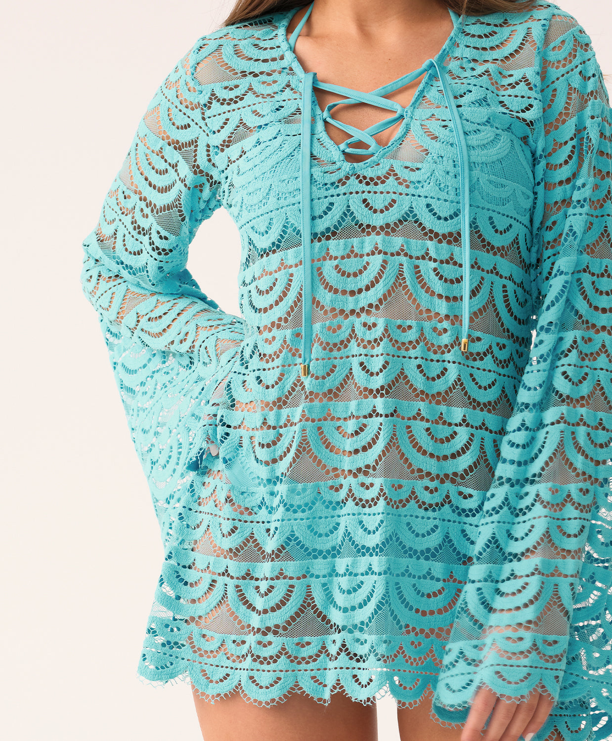 A close-up of a blue lace cover-up with long, bell sleeves and a lace-up v-neck.