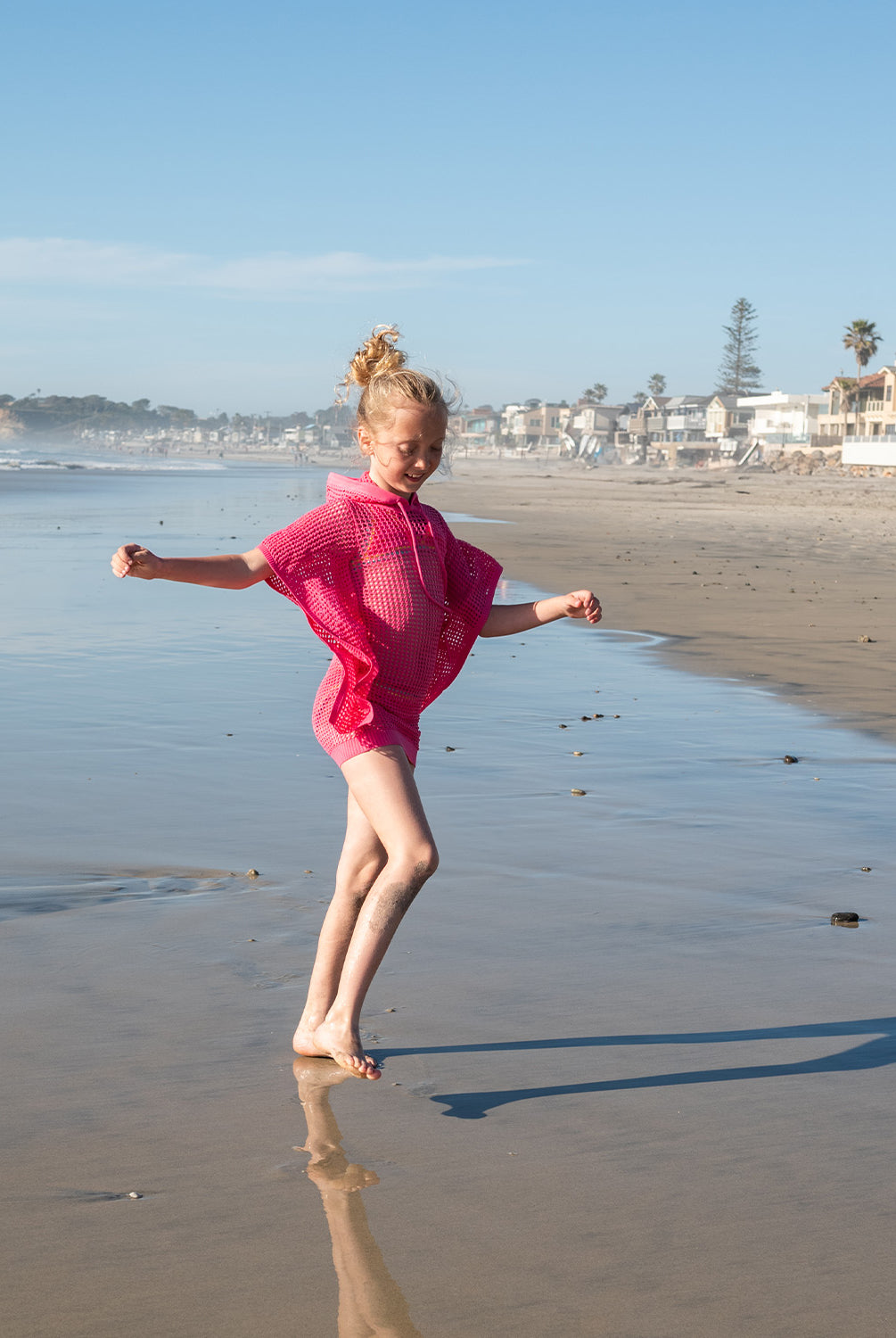 Kids Hot Pink Reagan Poncho with cozy hood and drawstrings, perfect for breezy beach days and post-swim comfort.