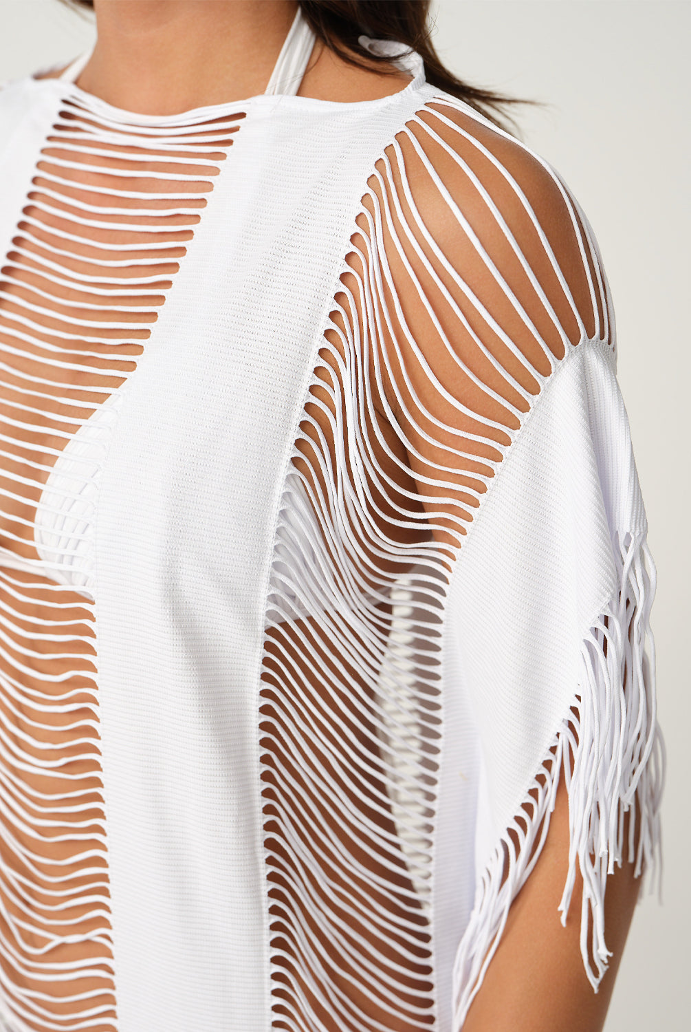 White mesh cover-up with fringe details on a plain background