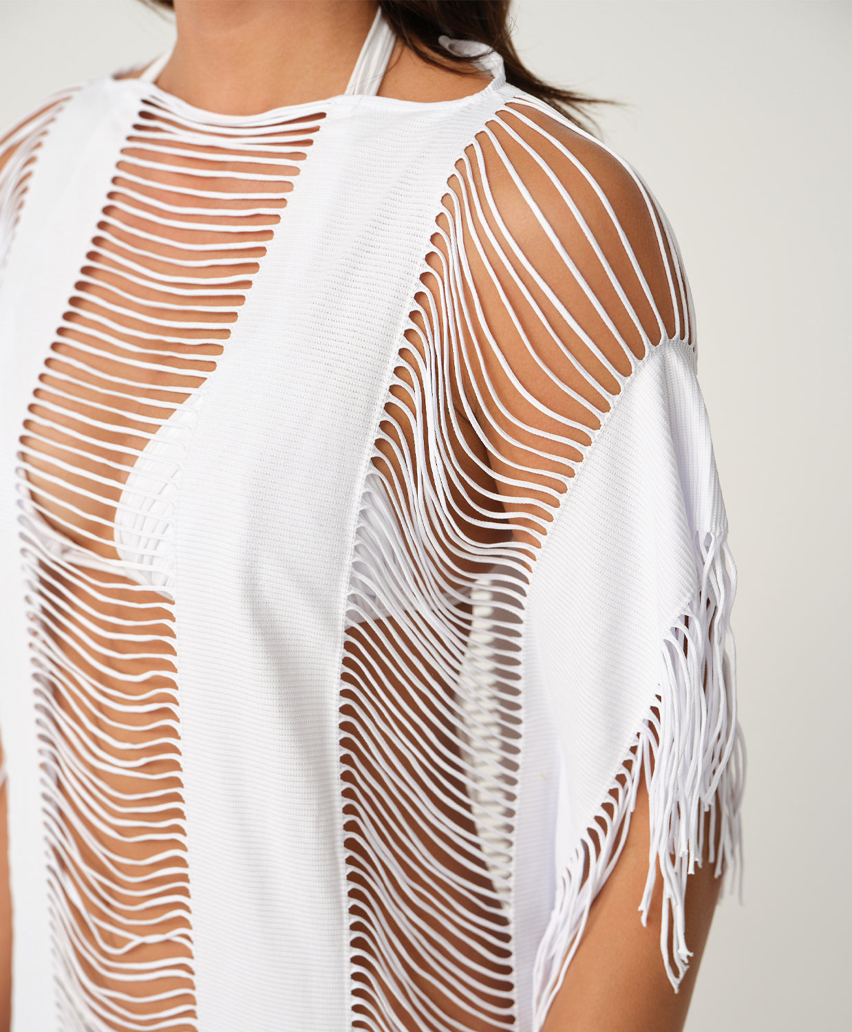 White mesh cover-up with fringe details on a plain background
