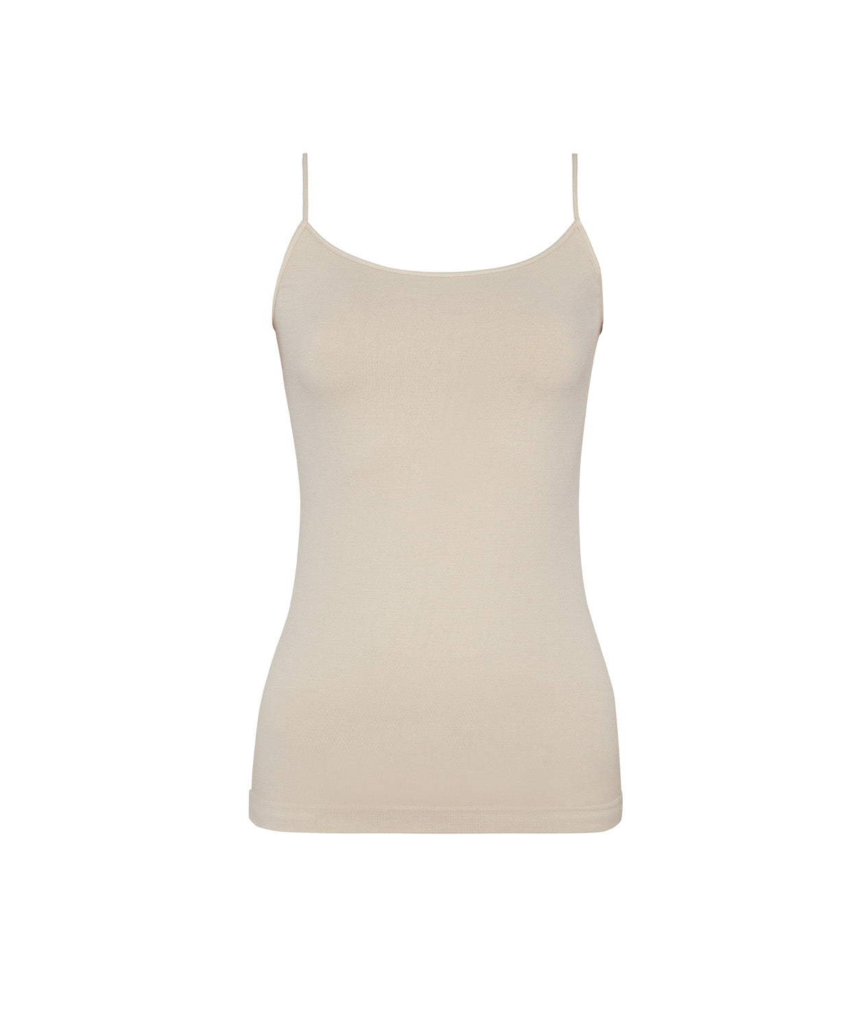 A woman wearing a nude tank top and matching shorts standing against a white wall.