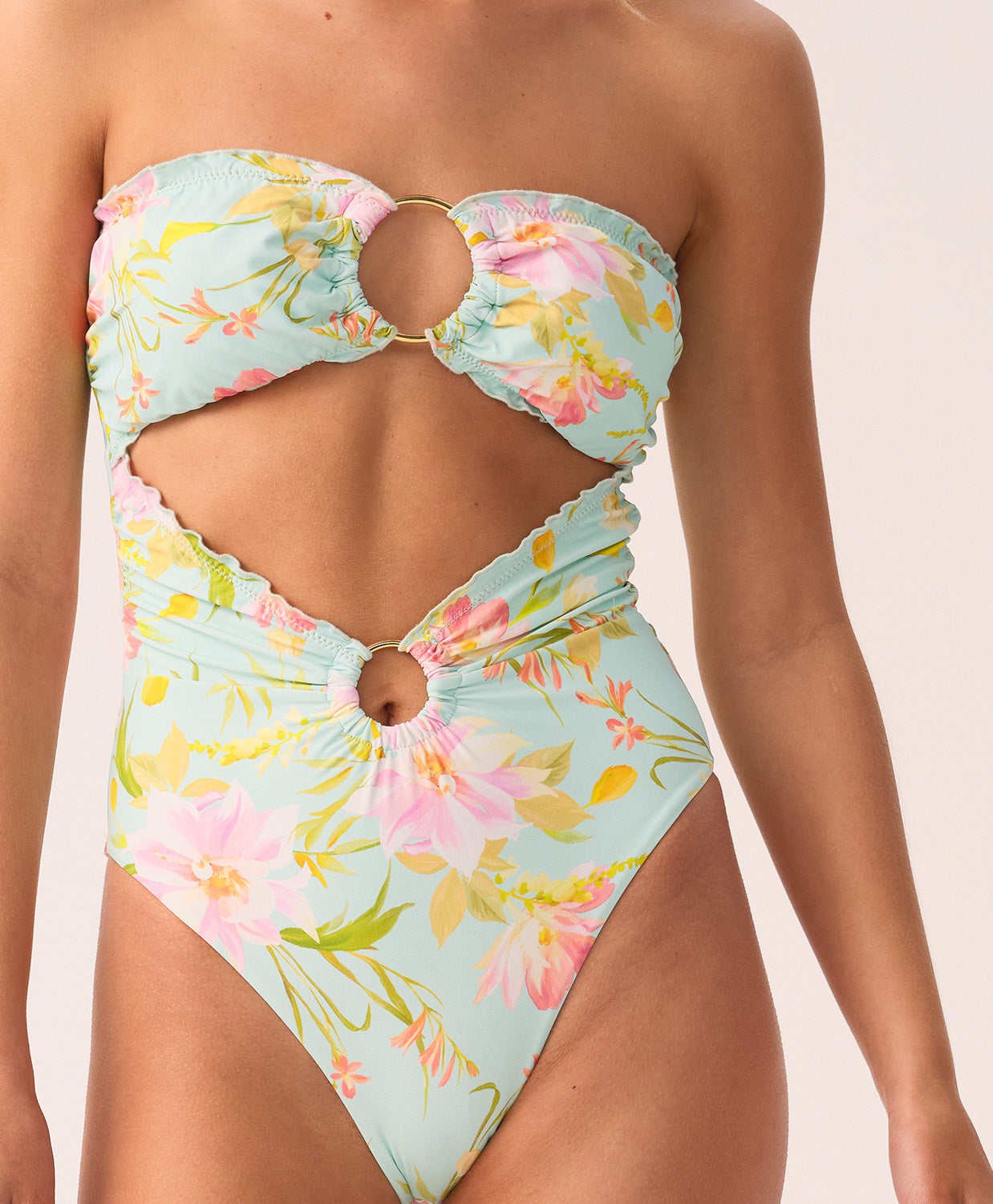 Woman wearing a floral-patterned swimsuit with cut-out design on a neutral background