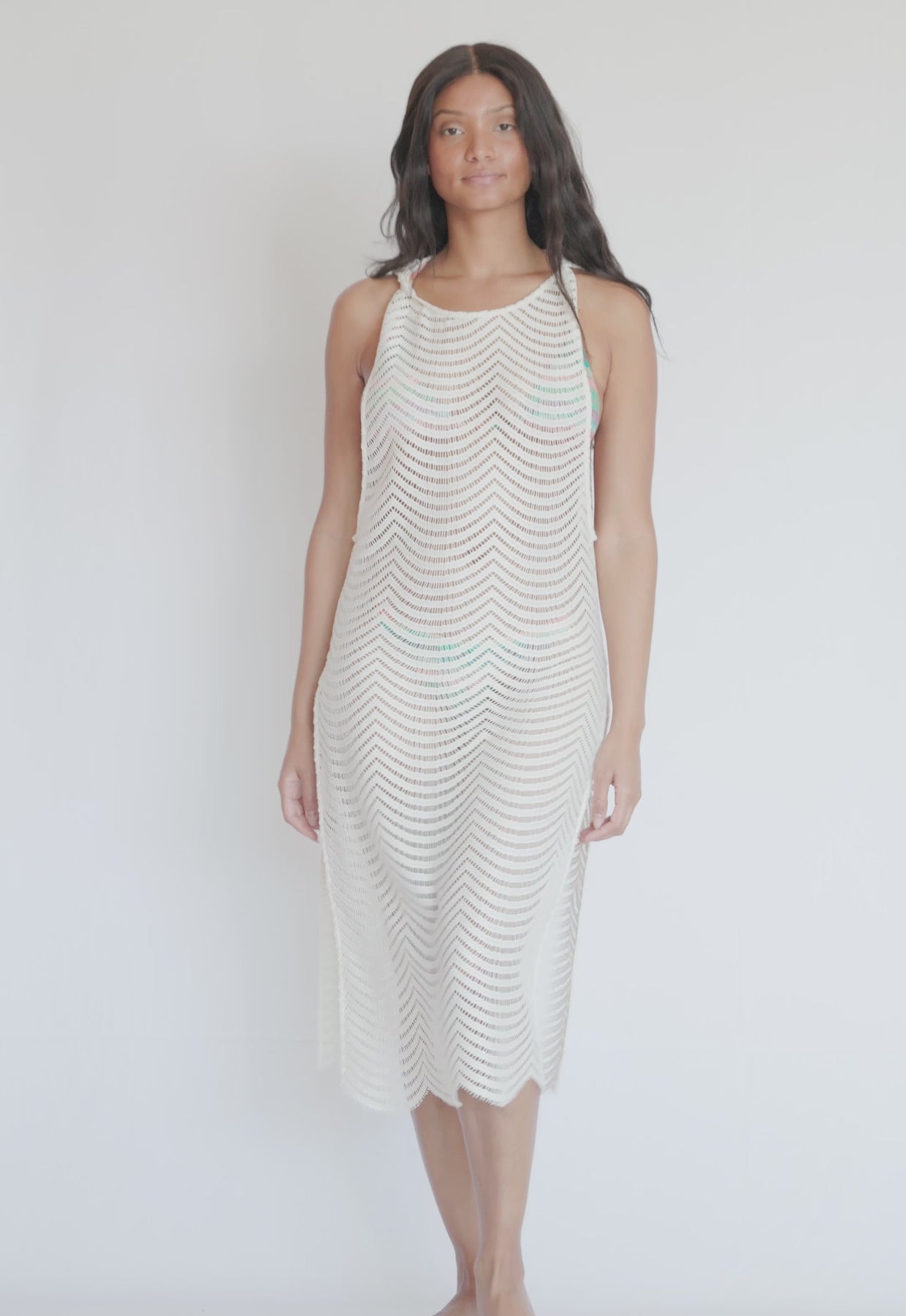 A woman wearing an ivory mid length dress spinning in front of a white wall.