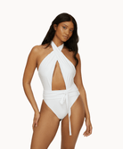 Woman wearing a white one piece in front of a white background.