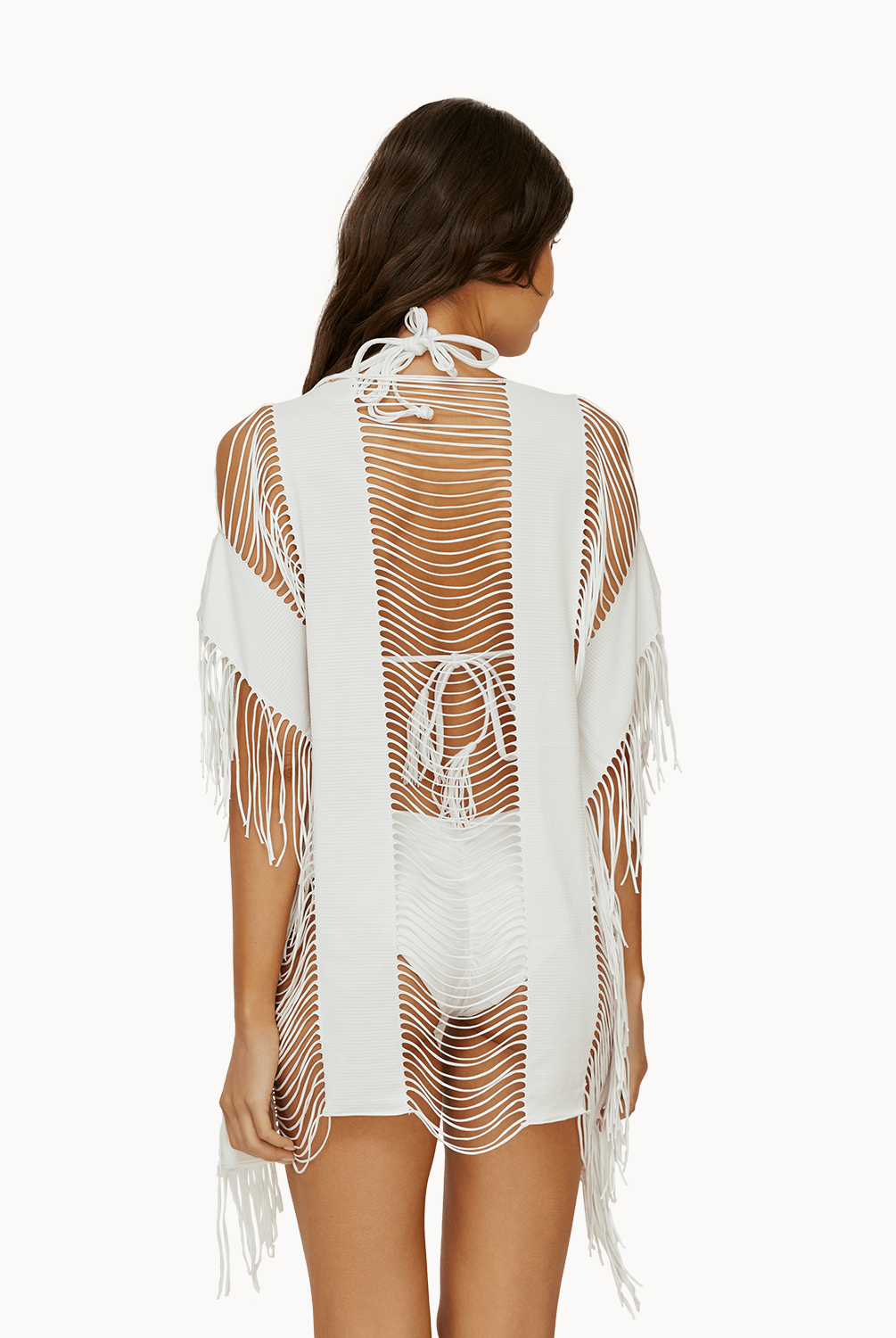 Back view of woman wearing a white fringe cover up in front of a white background.