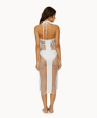 Back view of woman wearing a white fringe dress in front of a white background.