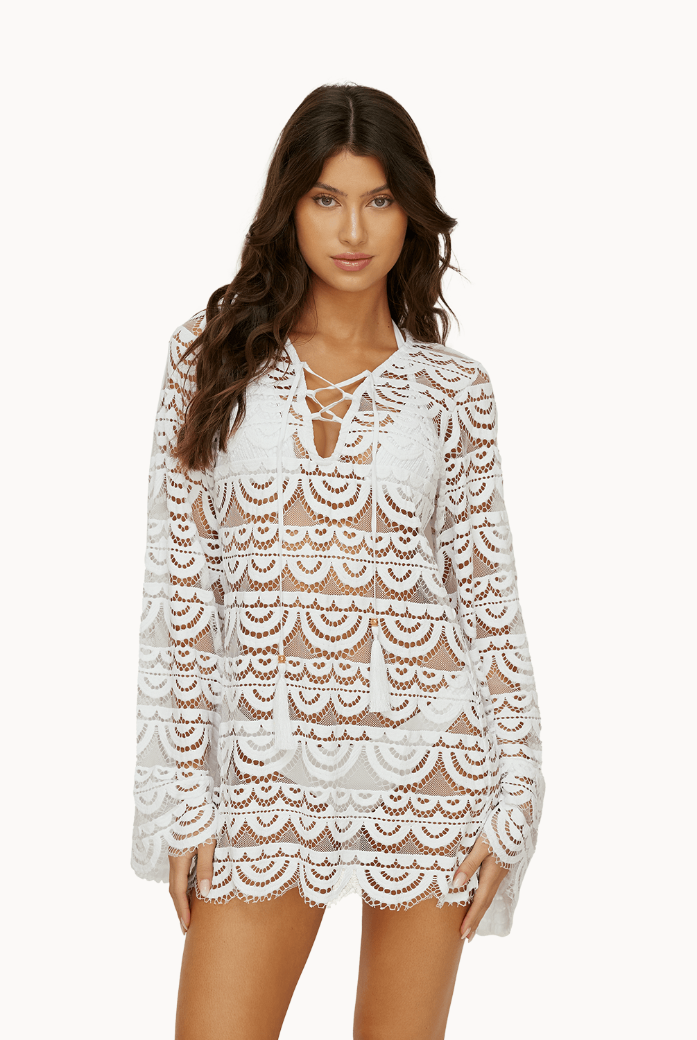 Woman wearing a white lace tunic in front of a white background.