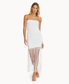 Woman wearing a strapless fringe dress against a white wall