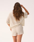 Woman wearing a textured beige outfit on a plain background