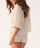 Woman wearing a white lace outfit on a plain background