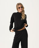 Woman wearing a black outfit with sunglasses on a white background