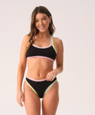 Woman wearing a black bikini with colorful trim on a white background