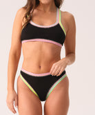 Woman wearing a black bikini with colorful trim on a white background