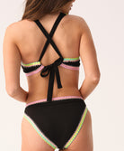Woman wearing a black bikini with colorful trim on a white background