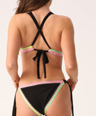Woman wearing a black bikini with colorful trim on a white background