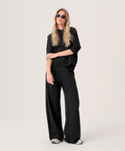 Woman wearing a black outfit with sunglasses on a plain background