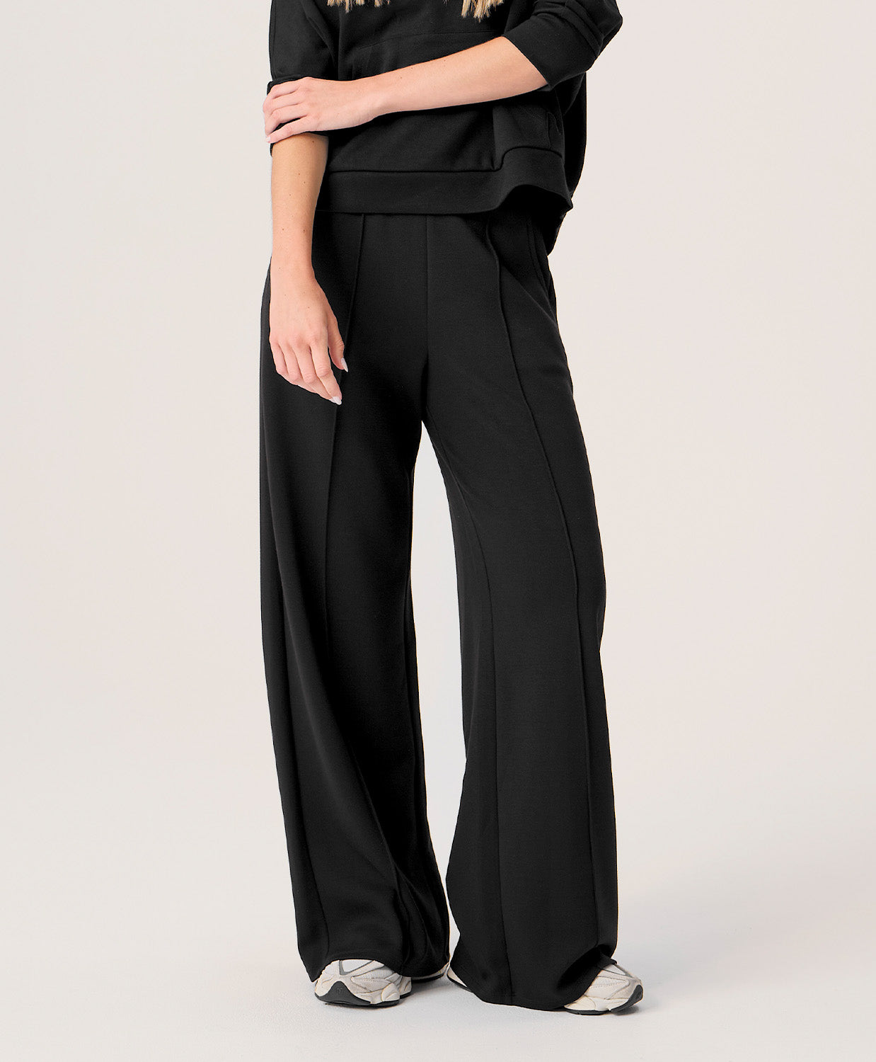 Woman wearing black wide-leg pants on a plain background