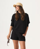 Woman wearing a black outfit with a beige cap on a white background
