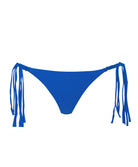 A blue bikini bottom with fringe sides against a white wall.