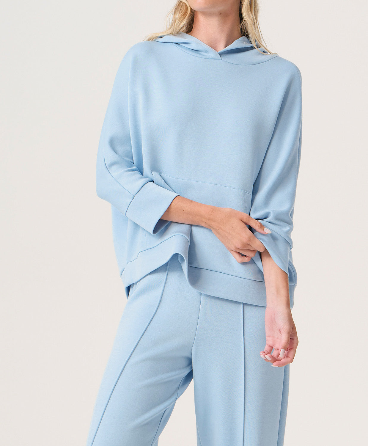Woman wearing a light blue hoodie and pants set on a white background