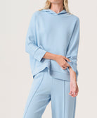 Woman wearing a light blue hoodie and pants set on a white background