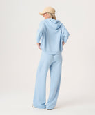 Woman wearing a light blue hoodie and pants with a beige cap on a white background