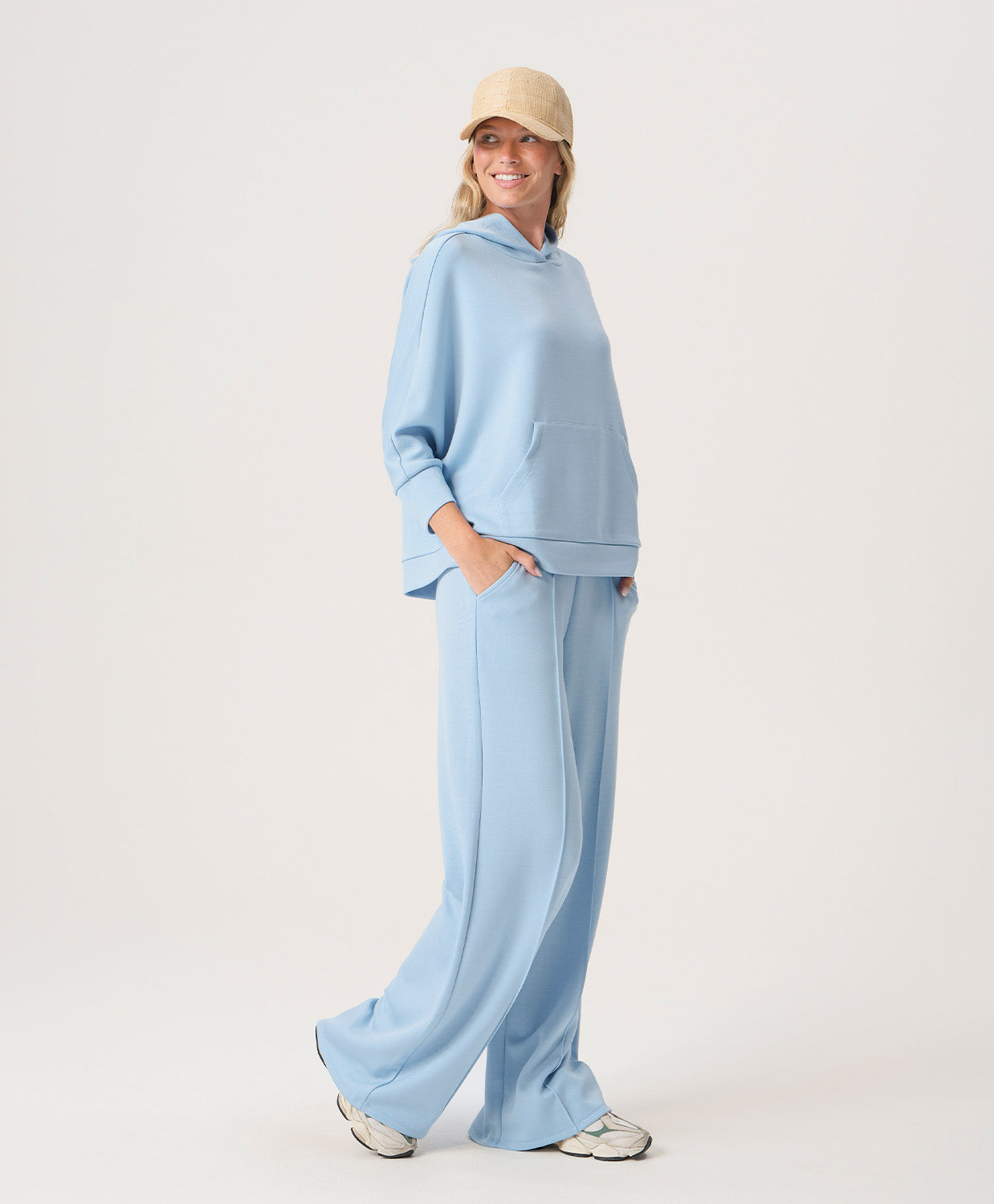 Woman wearing a light blue outfit with a matching cap on a plain background