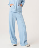 Woman wearing a light blue outfit with wide-leg pants on a white background