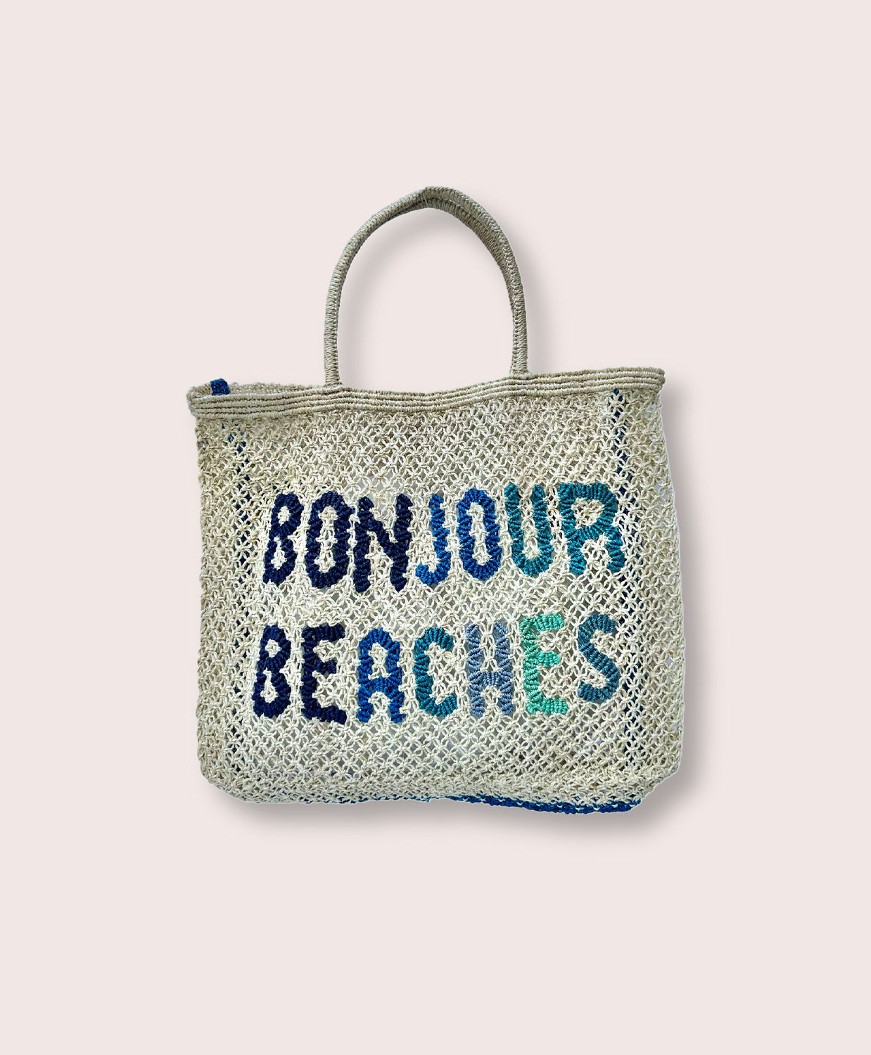 A purse/tote that says "Bonjour Beaches" in blue against a white wall.