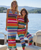 A blonde woman wearing a color block dress and a brunette woman wearing a color block top and pant set. Both woman are on a boat on a lake.