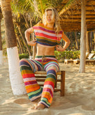 Woman wearing a colorful striped outfit on a tropical beach.